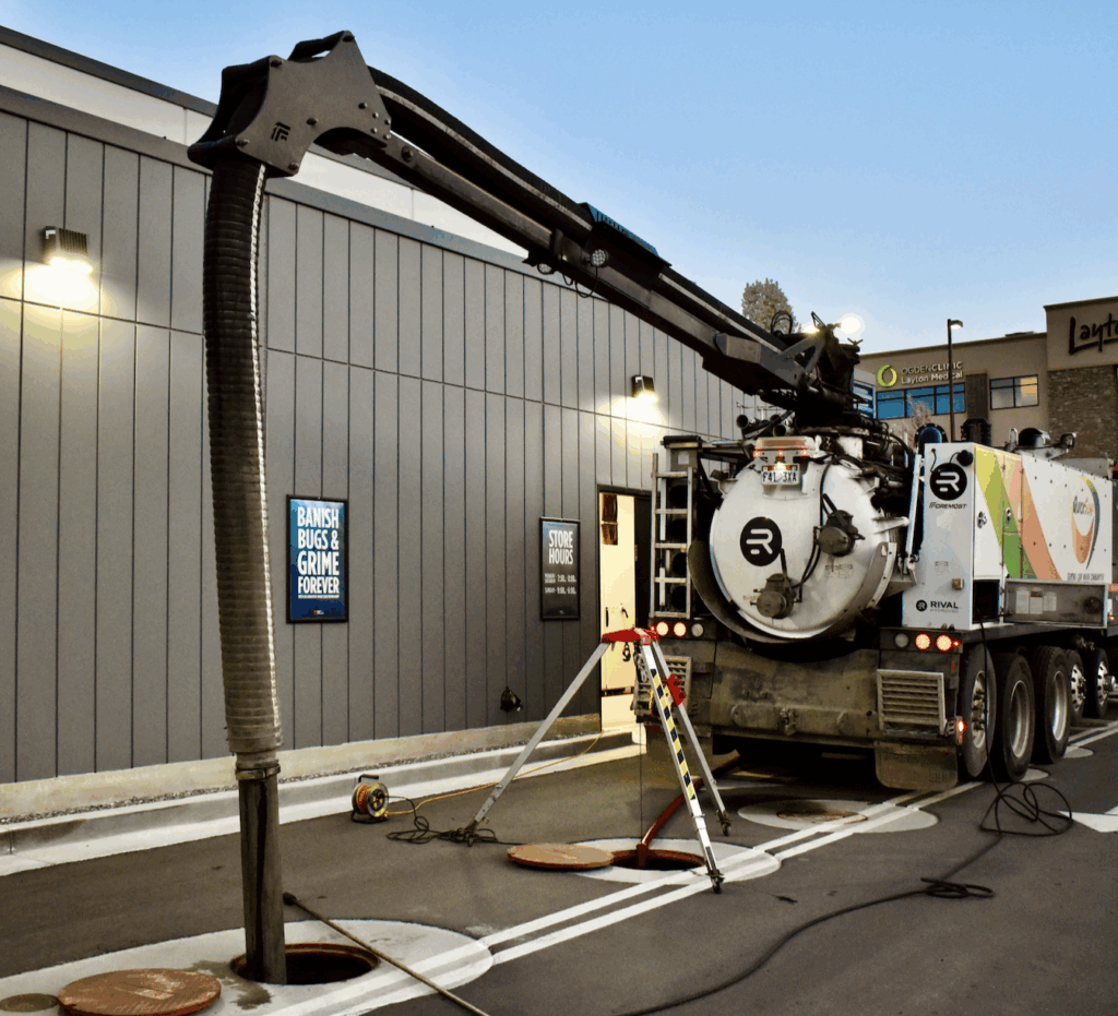 Hydrovac vacuum truck cleaning sludge and debris from car wash sump pit.